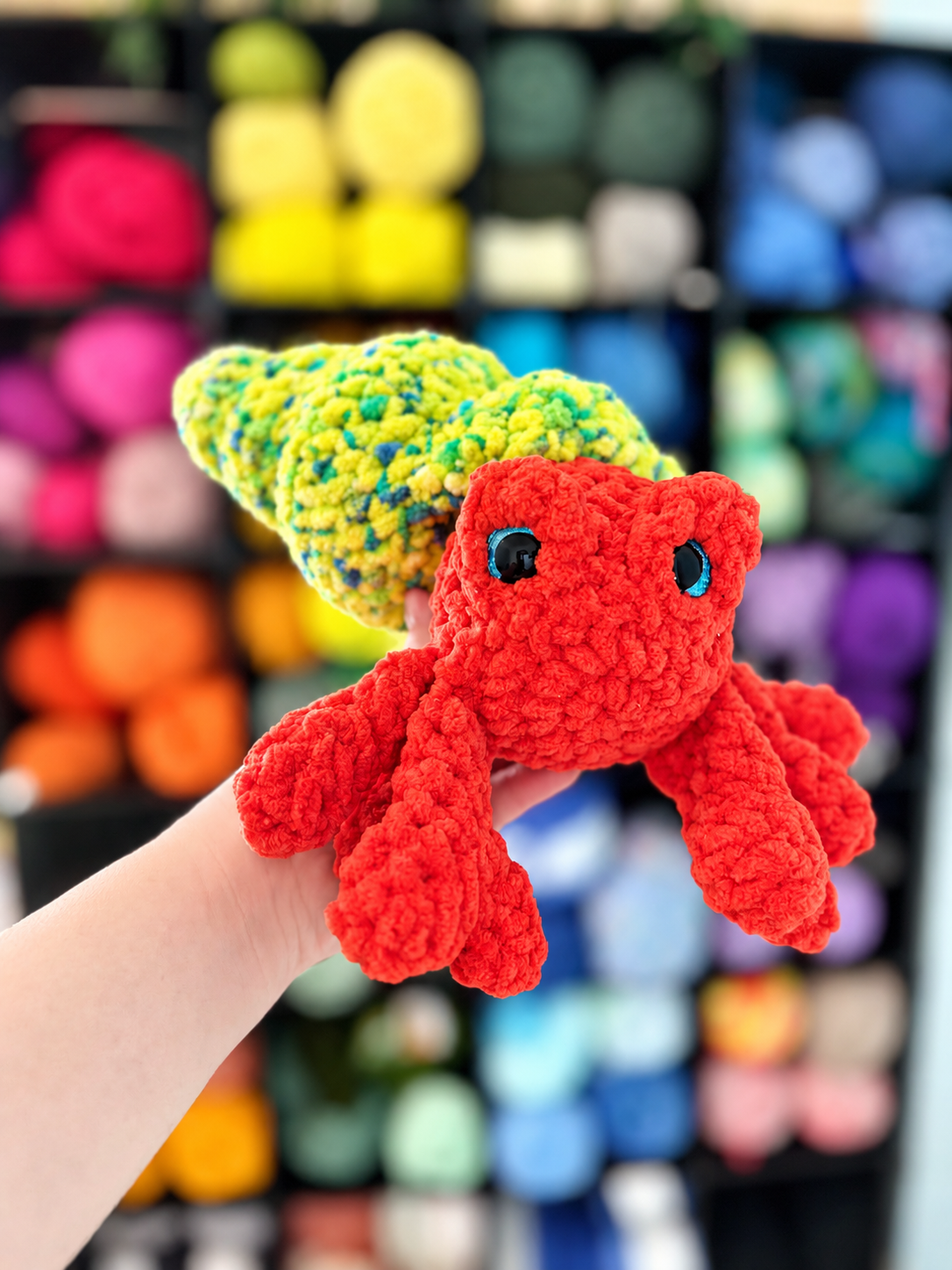 A peach crocheted octopus with teal-tipped tentacles and big dark eyes